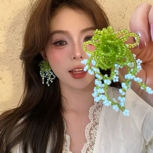 Detail of handmade beaded flower earrings with white tassels on a model for display