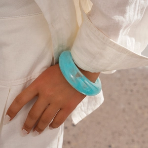 Close-up of a light blue marble resin bangle on a woman's wrist with a natural look