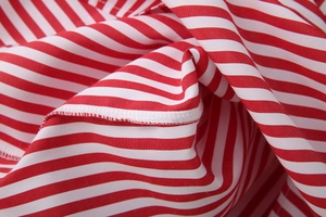 Macro shot of red and white striped poplin fabric showing high-quality white lockstitch seams