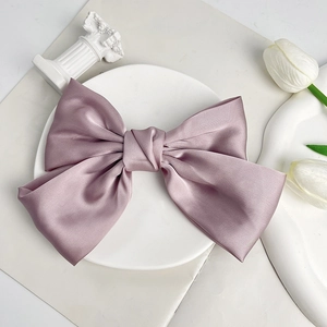 Detail of elegant dusty pink satin bow hair clip on a white decorative platter