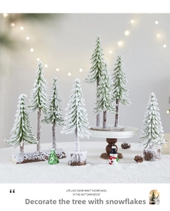 Close-up of snowy miniature Christmas trees with pine cones and snowman on wood base