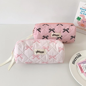 Detailed view of pink and white quilted pouches with bow patterns and ribbon zipper pulls