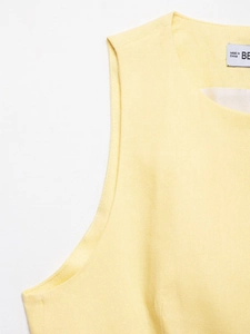 Macro shot of pale yellow sleeveless vest showing linen texture and neckline detail