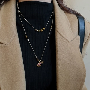 Vue détaillée du collier en œil de tigre et pendentif poney doré sur un mannequin