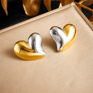 Minimalist two-tone heart stud earrings in gold and silver finish on silk background