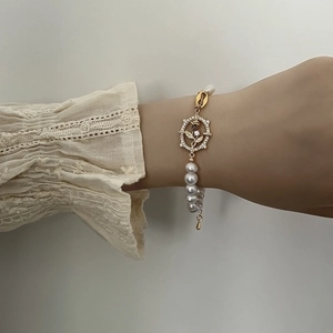 Detail of natural freshwater pearl bracelet with golden rose pendant and shell charm