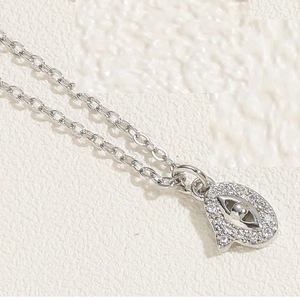 Macro shot of silver evil eye and letter D pendant necklace with white zircons