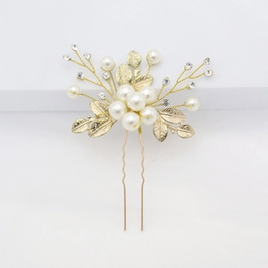 Detail of bridal hair pin with white pearls, small rhinestones and gold metal leaves
