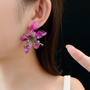 Close-up of vintage flower earrings with purple resin petals and green beaded centers