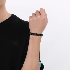 Gros plan d'un bracelet gourmette noir en acier inoxydable porté au poignet pour un look moderne