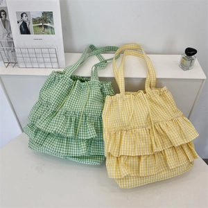 Close-up of layered ruffles and drawstring closure on plaid canvas tote bags