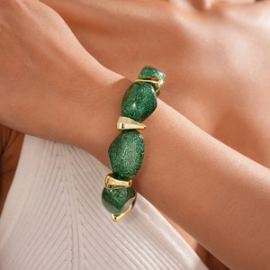 Close-up of chunky green glitter resin beads and gold metal spacers on a female wrist