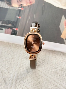 Detail of vintage oval quartz watch with rose gold case and brown leather strap on magazine