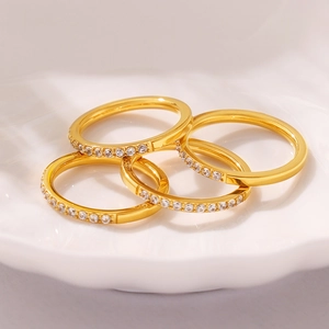 Set of four 18K gold plated zircon rings displayed on a white ceramic wave tray