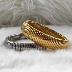 Dettaglio macro di bracciali Tubogas oro e argento con trama metallica a spirale