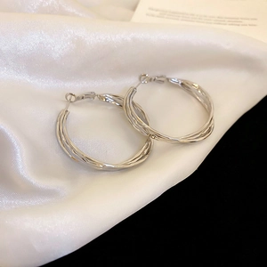 Macro detail of twisted silver hoops showing intricate metal texture on silk fabric