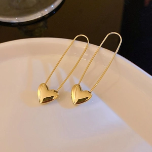 Elegant gold heart safety pin earrings with a minimalist design and polished metallic finish