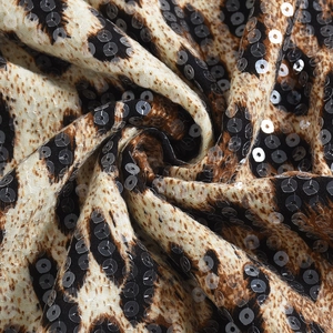 Détail macro du tissu imprimé léopard avec paillettes scintillantes et texture douce