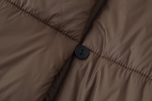 Gros plan sur la veste matelassée marron avec texture et boutons noirs