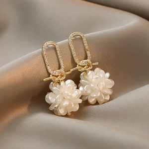 Detail view of flower drop earrings with inlaid rhinestones and white beaded floral clusters