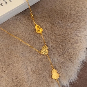 18k gold plated necklace with three textured wulu pendants on a soft plush backdrop