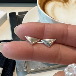Detail of minimalist S925 sterling silver triangle stud earring held by hand