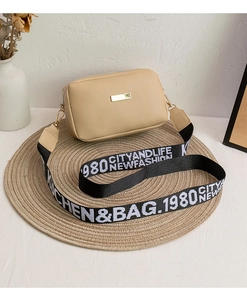 Close-up of beige lychee textured shoulder bag with chic wide lettered crossbody strap