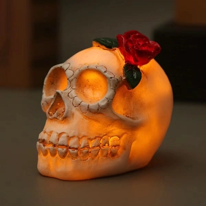 Macro shot of a resin skull LED lamp with a red rose top and warm orange light glow