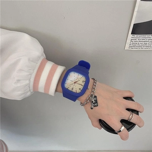 Square digital watch with blue silicone strap and silver chain bracelet on wrist