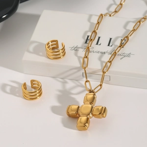 Vue détaillée du collier à pendentif croix dorée et des boucles d'oreilles triples