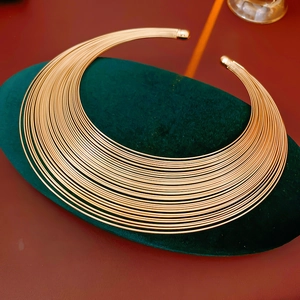 Detailaufnahme der minimalistischen mehrreihigen Goldhalskette auf grünem Samtkissen