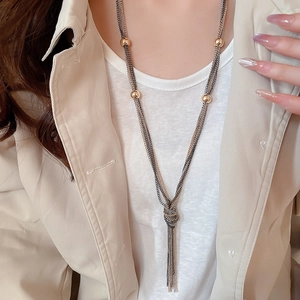 Close-up of multilayered mixed metal chain necklace with knotted tassel and gold beads