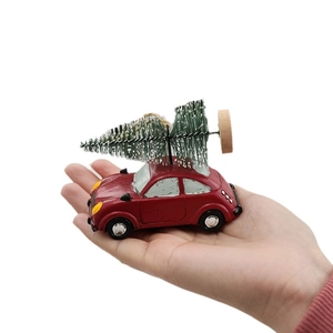 Miniature vintage red car resin pendant with a snowy Christmas tree held by a hand