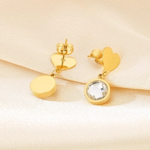 Golden heart earrings with round crystal drops on soft silk background for women
