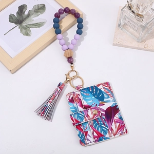 Close-up of tropical leaf pattern card wallet with silicone beaded wristlet and gold hardware