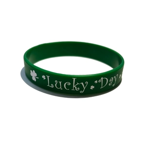 Detail of green silicone wristband featuring white Lucky Day text and clover pattern