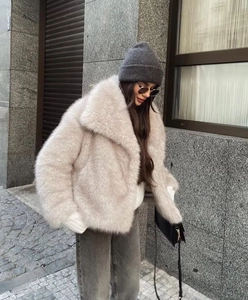 Close-up of light beige faux fur jacket featuring plush texture and large lapel collar