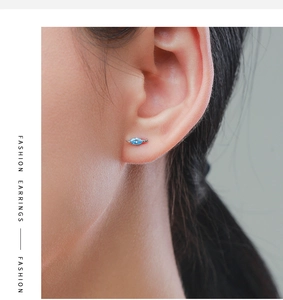 Gros plan d'une puce d'oreille avec pierre bleue en forme de feuille sur le lobe