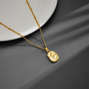 Collier en acier titane avec chaîne perlée dorée et pendentif rose blanche en nacre