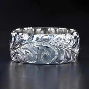 Polished silver ring with embossed vine pattern on a high-gloss metallic surface