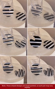 Detail of hand-painted striped acrylic hoop earrings with unique texture on a glass tray