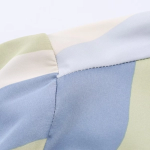 Macro shot of stitching details and multi-color patchwork on striped satin blouse