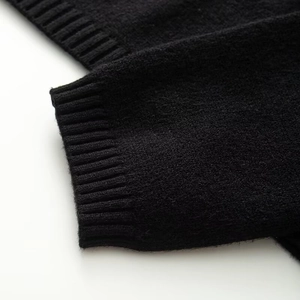 Detailed close-up of the ribbed cuff and soft knit texture on this black bow sweater