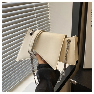 Detail of a creamy white geometric chain bag with a triangular flap and silver metal strap
