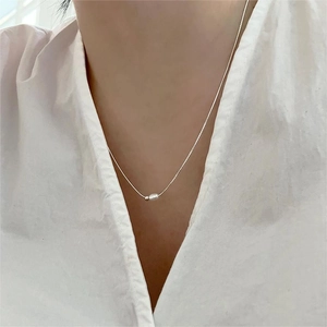 Detailed view of minimalist S925 sterling silver pearl bead necklace on model with white shirt