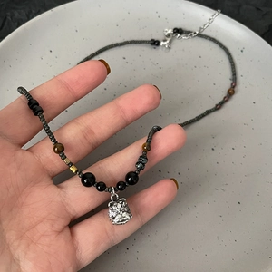 Detail of beaded necklace with black beads and silver guardian lion pendant
