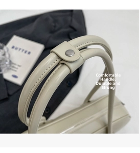 Detailed close-up of sturdy cream faux leather handles and precise stitching on the tote