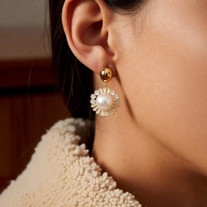 Detail of elegant gold-plated pearl drop earrings with sparkling zircon accents on model
