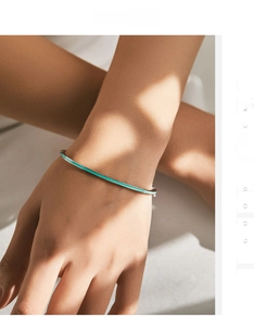 Close-up of a minimalist s925 silver bangle with mint green enamel on a model's wrist