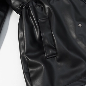 Détail de la poche de veste en cuir noir avec bouton pression et coutures fines
